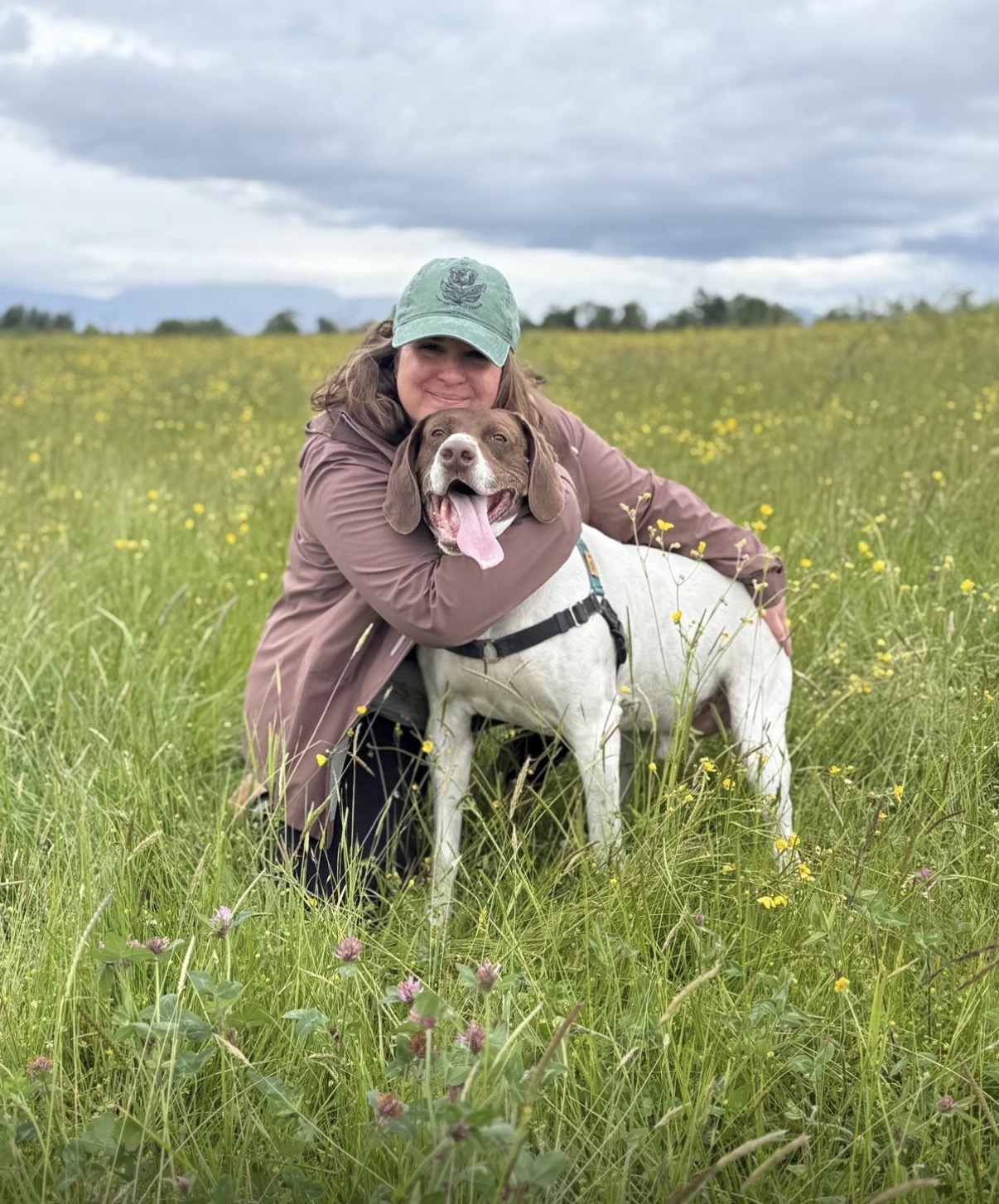 Domenica hugging Eddy in a green meadow filled with yellow wildflowers