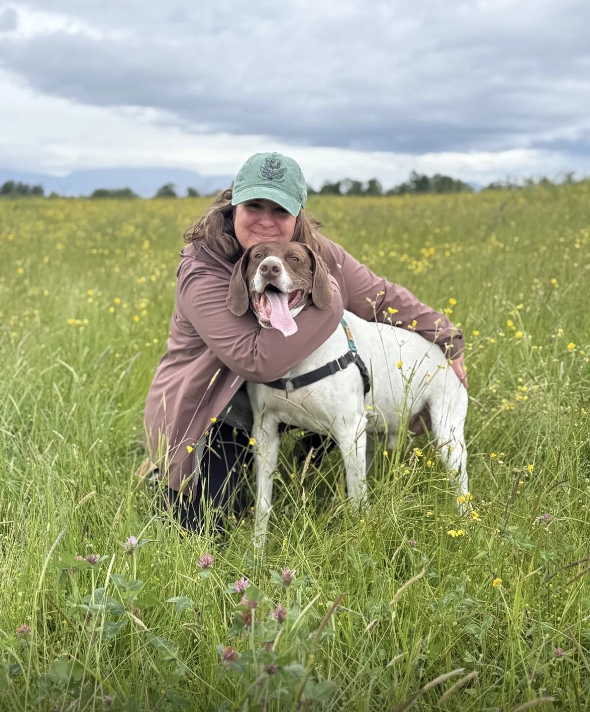 Domenica hugging Eddy in a green meadow filled with yellow wildflowers